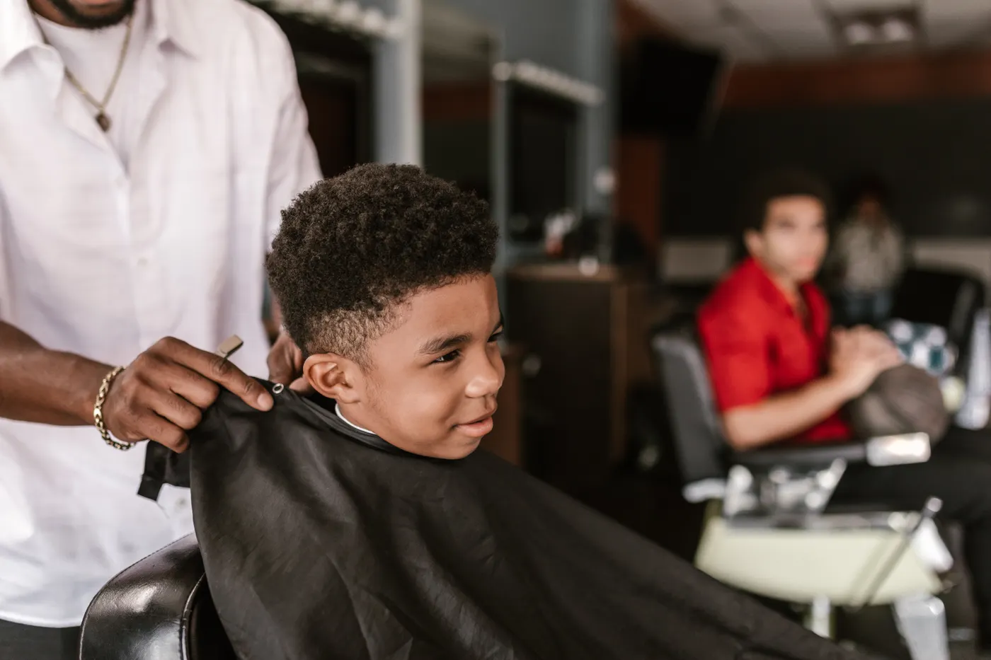 Jeune garçon souriant pendant sa coupe au salon