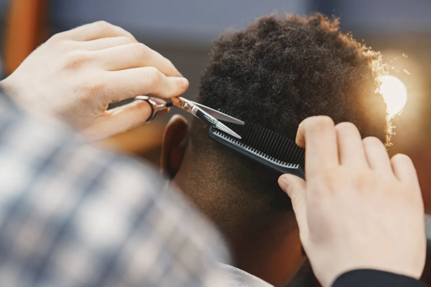 Coiffeur qui travaille une coupe afro aux ciseaux et au peigne