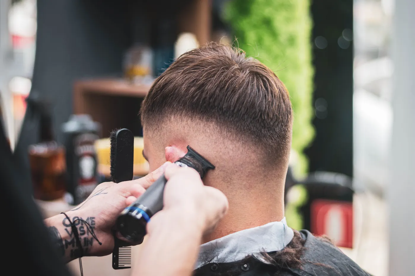 Coiffeur qui taille les cheveux d’un jeune homme à la tondeuse